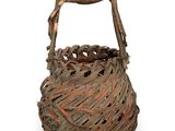 un panier en osier muni d'une poignée en bois, sur fond blanc