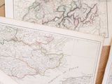 many maps of europe on a table with a cup of coffee