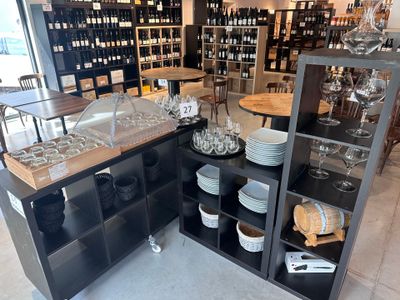 Des bouteilles de vin et des verres sont exposés dans un caviste.
