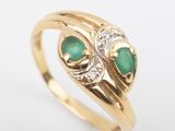 a close up of a gold ring with two emerald stones