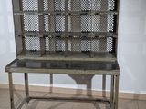 a metal shelf with a glass top on a tiled floor