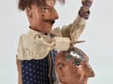 a doll that is sitting on top of a man ' s head