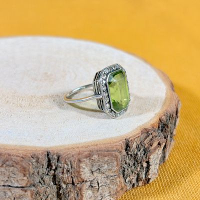 un gros plan d'une bague ornée d'une pierre verte posée sur un morceau de bois