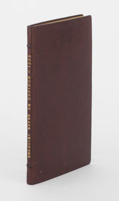 un livre marron orné de lettres dorées, posé sur une surface blanche