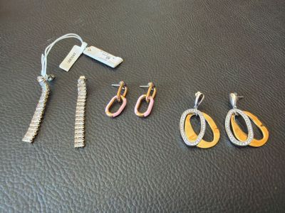 trois paires de boucles d'oreilles et une paire de ciseaux posés sur une table