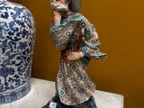 a figurine of a man with a hat on a table next to a vase