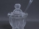 un bocal en verre contenant une cuillère, posé sur une table