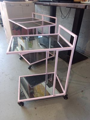 un chariot rose surmonté de trois étagères en verre