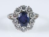 a close up of a sapphire and diamond ring on a white surface