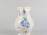 a white vase with blue flowers on it sitting on a table
