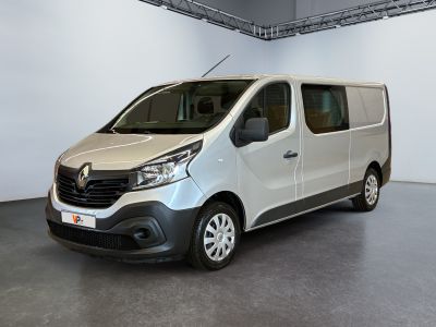 La camionnette blanche est garée dans une grande pièce au sol gris.