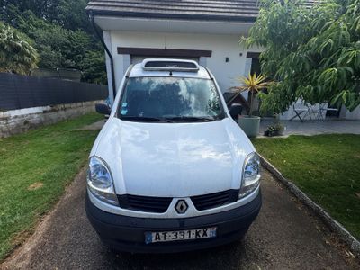 une petite camionnette blanche garée devant une maison