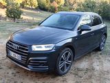 the black audi suv is parked on the dirt in the field