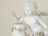 a statue of a cupid sitting on top of a cake