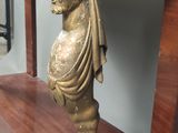 une statue représentant un garçon debout sous une table en bois