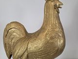 gold rooster statue on stand on white surface with white background