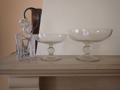 deux bols en verre posés sur une table, avec une bouteille d'alcool en arrière-plan