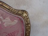 a pink chair with a gold frame and a white wall