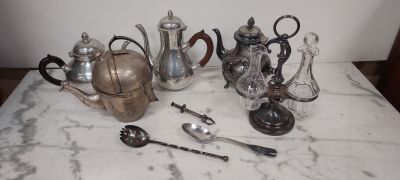 de nombreuses théières et cuillères en argent posées sur une table