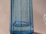 a blue glass bottle sitting on a table next to a diamond