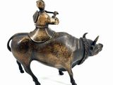 bronze figurine of a man riding a bull with a woman on it
