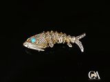 une broche en forme de poisson argenté aux yeux turquoise sur un fond noir