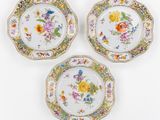 trois assiettes ornées de motifs floraux et d'une bordure dorée
