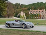 a silver sports car driving down the road in front of a castle