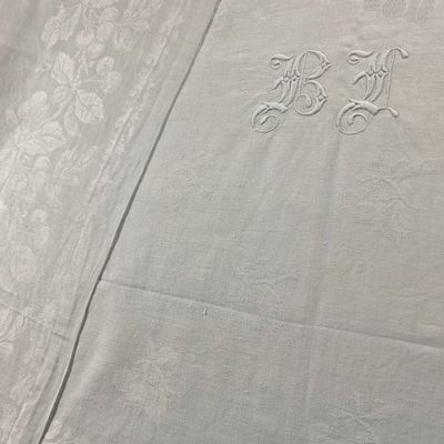a close up of a white table cloth with a monogram on it