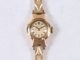 a gold wrist watch with a white face on a white surface