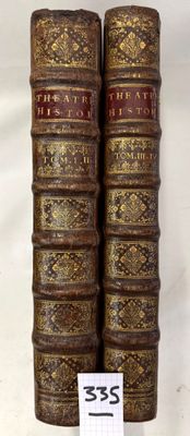 two old books are stacked on top of each other on a white surface