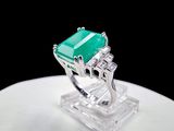 an image of a ring with a green stone on top of a white plate