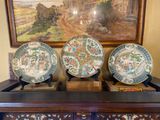 three plates sitting on top of a dresser in front of a painting