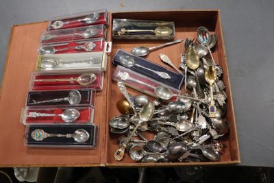 une boîte remplie de cuillères en argent et des cuillères posées sur une table