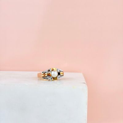 un gros plan d'une bague en or et perles sur fond rose