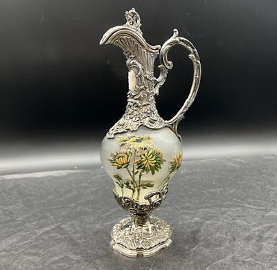 un vase ancien en métal argenté, orné de fleurs, posé sur une table