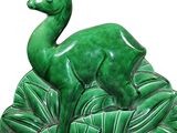 a green statue of a deer in the middle of a field