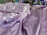 a bed with a purple comforter and purple sheets on it