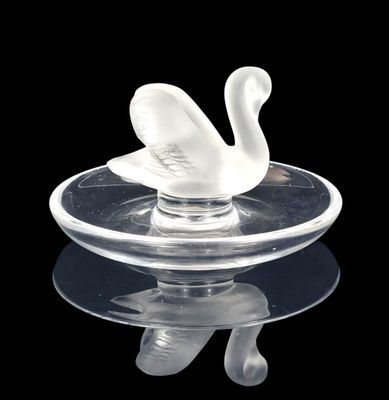 a glass swan sitting on top of a glass plate