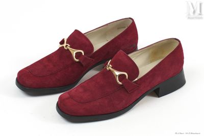 une paire de chaussures en daim rouge avec une chaîne dorée au talon