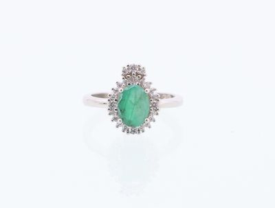 gros plan d'une bague avec une pierre verte entourée de diamants blancs