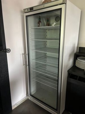 un réfrigérateur à porte vitrée dans un coin de la pièce
