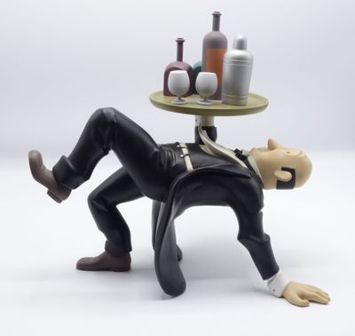 une figurine représentant un homme allongé sur une table sur laquelle se trouvent des bouteilles