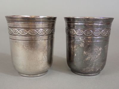 deux tasses en argent posées l'une à côté de l'autre sur une table