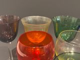 many different colored glasses sitting on a table