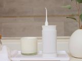 a white toothbrush sitting on a tray next to a candle