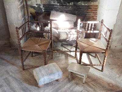 three wooden chairs sitting in front of a fire place