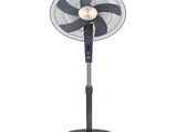 un ventilateur noir posé sur un support métallique, près d'un mur blanc
