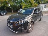 La voiture noire est garée sur le parking, près des arbres.