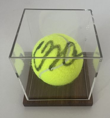 une balle de tennis dans une boîte transparente ornée d'un graffiti